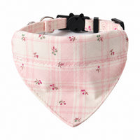 Collier bandana pour chien à carreaux rose pâle et crème, orné de petits motifs floraux, avec fermoir noir et anneau métallique, sur fond blanc.
