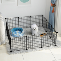 Un petit chien blanc dans sa cage à chiot d'intérieur de couleur noir, avec un petit panier et une gamelle à coté de lui