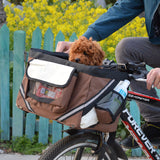 Un petit chien marron dans son panier à vélo de couleur marron qui se fixe bien sur le guidon du vélo
