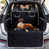 Un chien marron qui s'allonge dans un coffre de voiture sur un tapis de protection de couleur noir avec un gamelle bleu près de lui