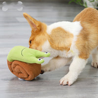 Un petit chien qui fouille quelque chose sur son jouet en forme d'escargot de couleur vert et marron