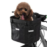 Un petit chien marron dans son panier à vélo de couleur noir et sur un fond blancqui sort sa langue