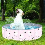 Un chien blanc profitant de sa piscine de couleur rose à motif patte de chien sur une pelouse à l'extérieur
