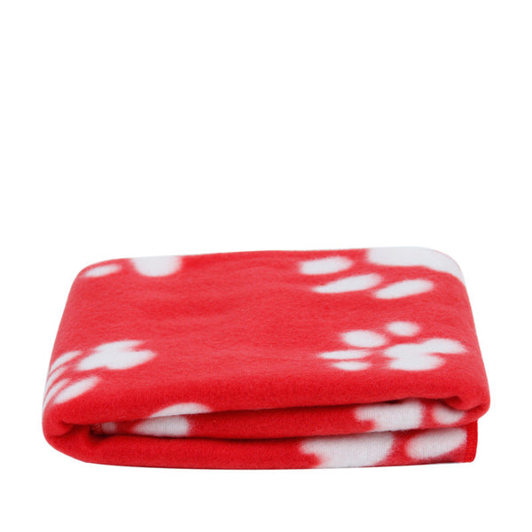 Couverture rouge avec des impressions pattes de chien pliée sur un fond blanc