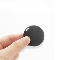 Un dispositif GPS bluetooth noir tenu par une main, sur un fond blanc