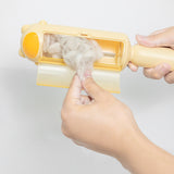 Une main entrain de sortir des déchets dans la cuve de la brosse anti poils à rouleau de couleur jaune et sur un fond blanc