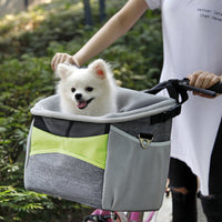 Un petit chien blanc qui s'assoie confortablement dans son panier à vélo pour chien de couleur gris