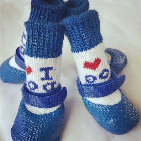 Quatre chaussettes imperméables pour chien, bleu marine et blanches, avec message décoratif et fermeture velcro, posées sur un fond clair.