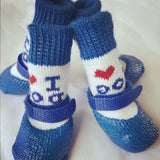Quatre chaussettes imperméables pour chien, bleu marine et blanches, avec message décoratif et fermeture velcro, posées sur un fond clair.