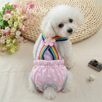 Small white-haired dog wearing a pink overall diaper with white polka dots and a multi-colored band. 