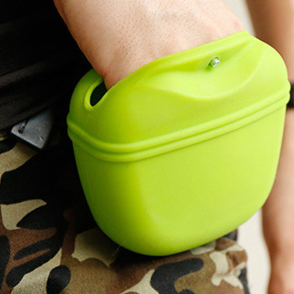 Une main qui cherche des friandises dans une sac à friandises pour chien en silicone de couleur vert