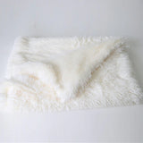 Une couverture pour chien en velours de couleur blanc sur un sol de couleur blanc