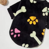 pull pour chien en polaire noire posé à plat avec des os et des pattes jaunes roses et verts