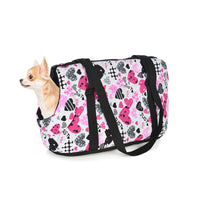 Petit chien dans son sac de transport pour chien à motifs de couleur rose