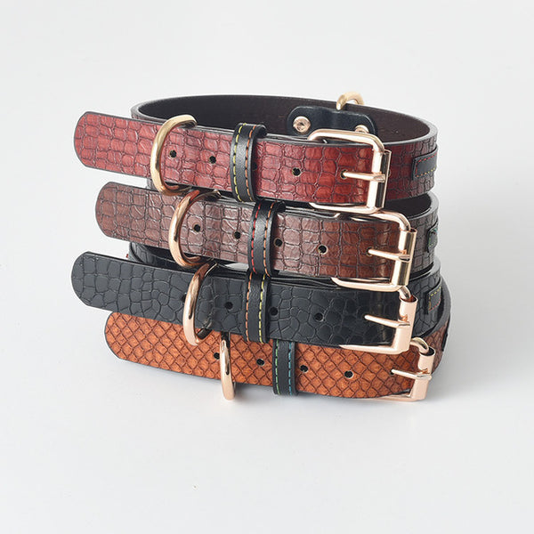 Plusieurs colliers pour chien en cuir sont empilés les uns sur les autres. Ces colliers ont tous un design différents et de couleurs différentes: rouge, marron, noir et marron clair. 